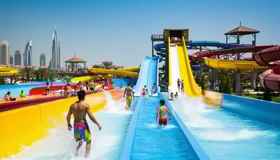 Families enjoying water slides and pools at a lively Dubai water park
